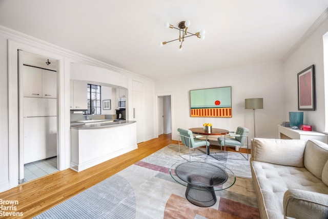 living room with a notable chandelier, ornamental molding, and light hardwood / wood-style flooring