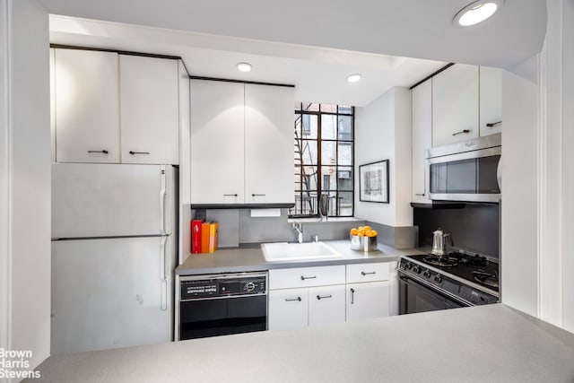 kitchen with black appliances, white cabinets, and sink