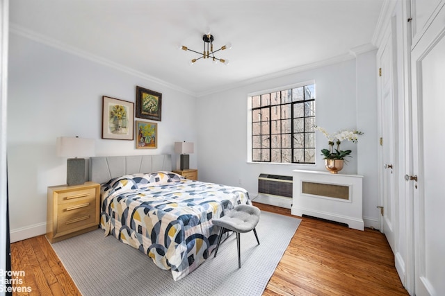 bedroom featuring an AC wall unit, a notable chandelier, ornamental molding, and hardwood / wood-style floors