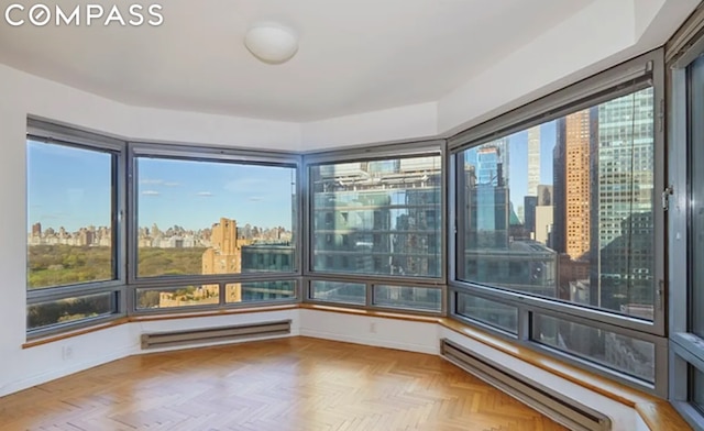 unfurnished sunroom featuring a baseboard heating unit and a city view