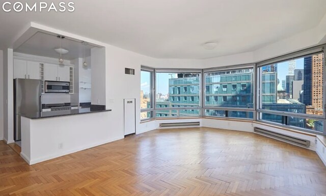 spare room with a healthy amount of sunlight, a baseboard heating unit, visible vents, and a city view