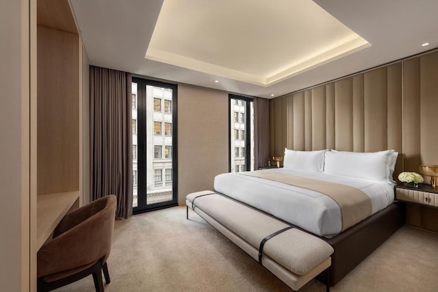 bedroom featuring a raised ceiling, access to outside, and light carpet