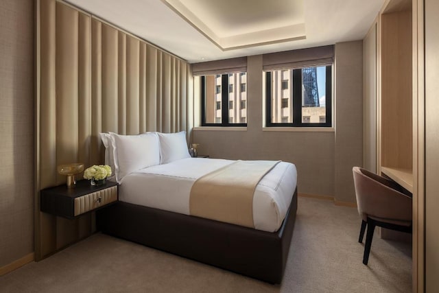 bedroom with a tray ceiling and light carpet