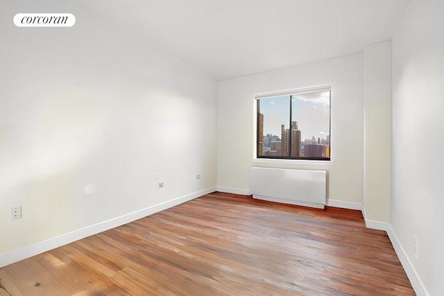 64 E 111th St Unit 1101, New York City, NY 10029 - unfurnished room featuring light wood-style flooring, baseboards, radiator heating unit, and vaulted ceiling