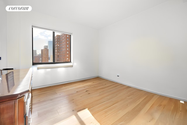 spare room with a view of city, visible vents, and light wood-style floors