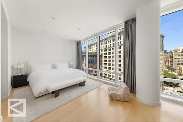 bedroom with floor to ceiling windows, hardwood / wood-style floors, and ornate columns