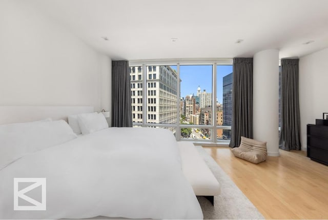 bedroom with a wall of windows, multiple windows, and hardwood / wood-style floors