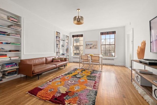 living area with radiator, light wood-type flooring, and built in shelves