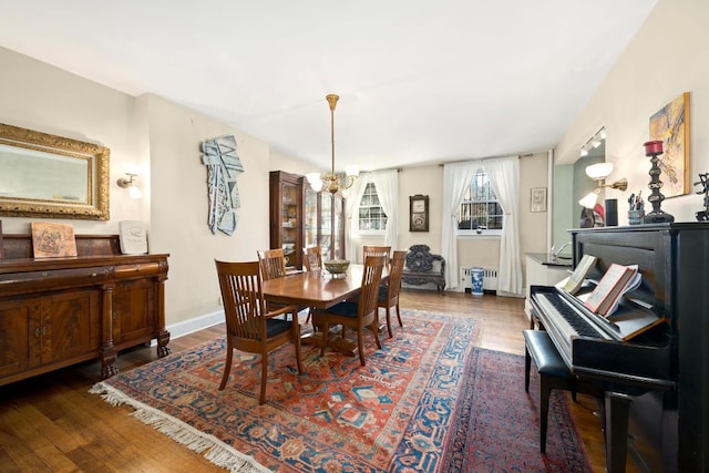 dining room with dark hardwood / wood-style floors, radiator heating unit, and an inviting chandelier