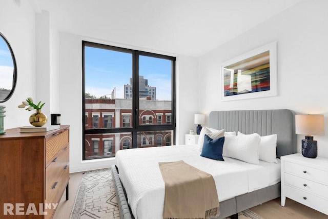 bedroom with floor to ceiling windows and light wood-type flooring