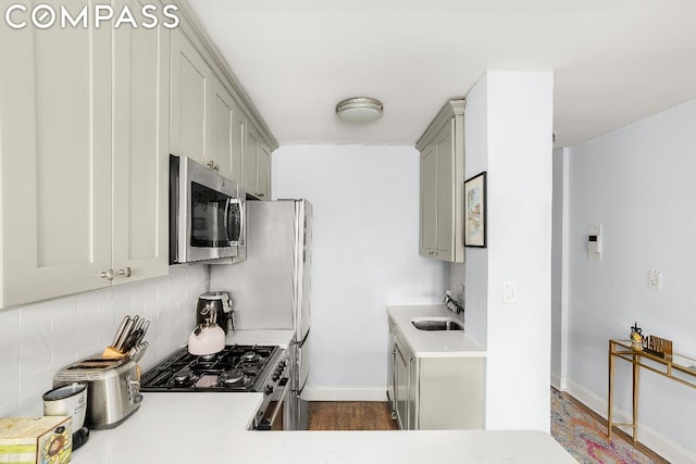 kitchen with appliances with stainless steel finishes, gray cabinetry, tasteful backsplash, and sink