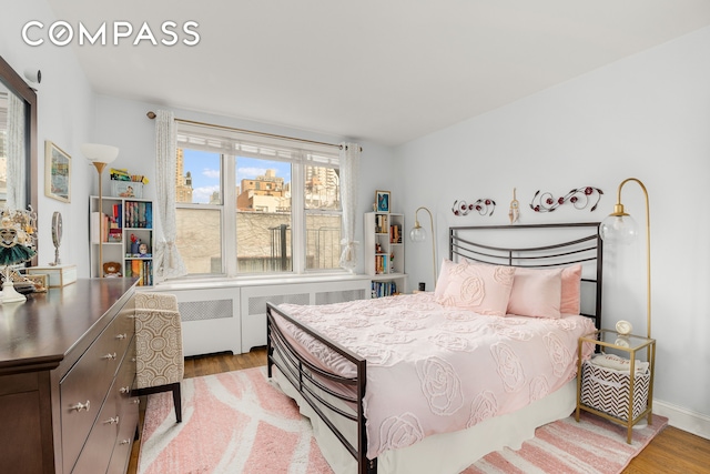 bedroom featuring radiator heating unit and wood finished floors