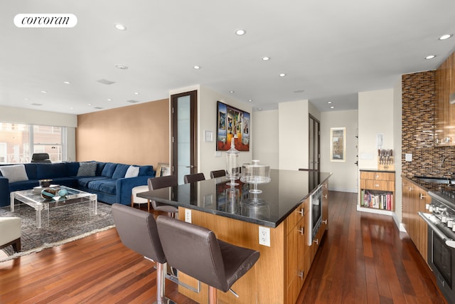 kitchen featuring a center island, a kitchen bar, decorative backsplash, stainless steel appliances, and dark hardwood / wood-style flooring