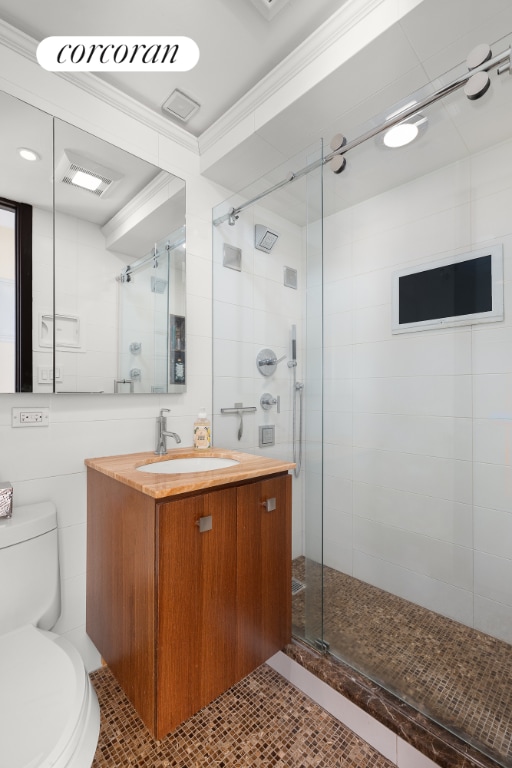 bathroom with a shower with shower door, vanity, tile walls, and toilet