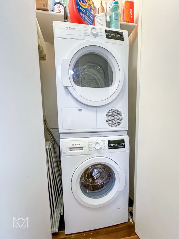 washroom featuring stacked washing maching and dryer and dark hardwood / wood-style flooring