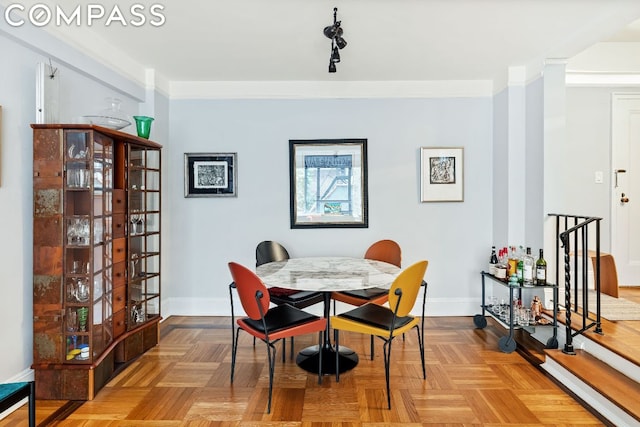 dining space with crown molding and light parquet floors