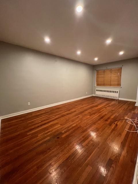 1241 E 98th St, New York City, NY 11236 - unfurnished living room featuring radiator heating unit, dark wood-type flooring, baseboards, and recessed lighting