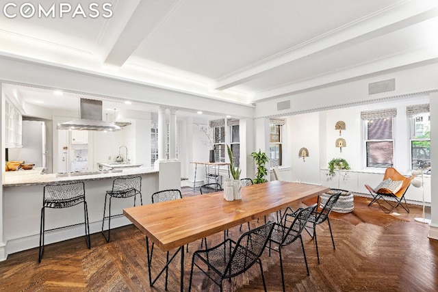 dining space featuring sink, dark parquet floors, and beamed ceiling