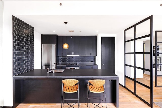 kitchen featuring pendant lighting, kitchen peninsula, sink, a breakfast bar area, and stainless steel fridge