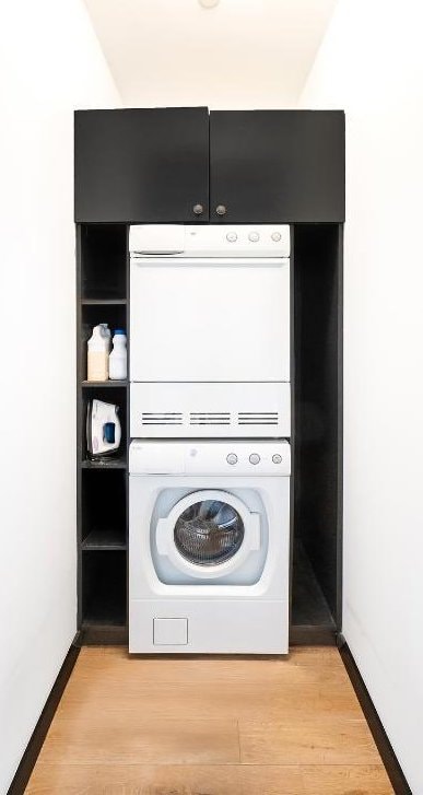 laundry room with stacked washer and dryer and light wood-type flooring