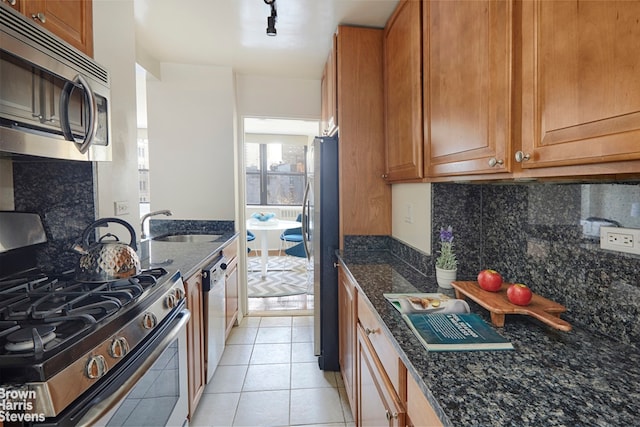 kitchen with stainless steel appliances, tasteful backsplash, dark stone counters, and sink