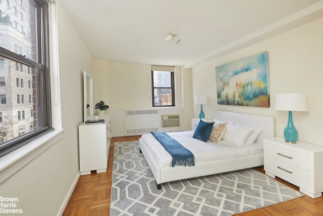 bedroom featuring light parquet flooring, radiator heating unit, and a wall mounted air conditioner