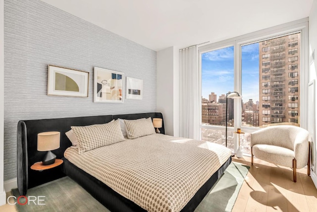 bedroom with floor to ceiling windows and light hardwood / wood-style floors