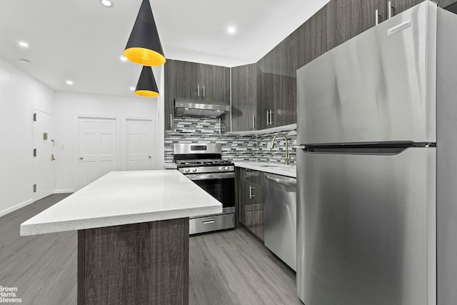 kitchen with sink, decorative light fixtures, light hardwood / wood-style flooring, appliances with stainless steel finishes, and decorative backsplash