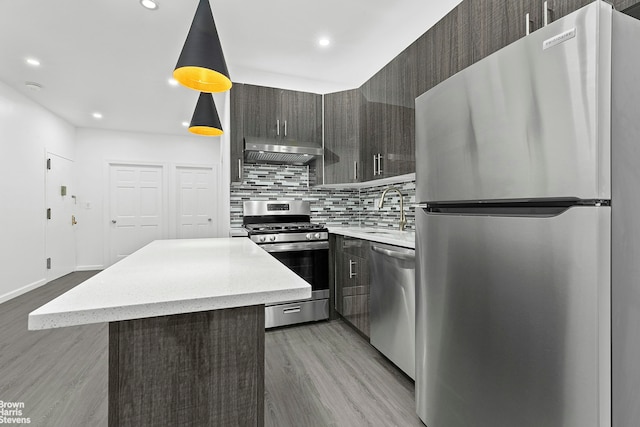 kitchen with tasteful backsplash, appliances with stainless steel finishes, a sink, modern cabinets, and under cabinet range hood