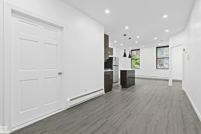 unfurnished living room with a baseboard heating unit and dark hardwood / wood-style floors