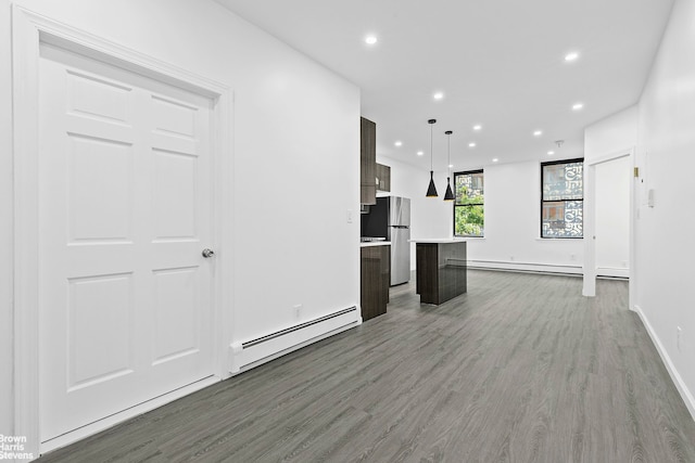 unfurnished living room with a baseboard heating unit, recessed lighting, baseboards, and wood finished floors