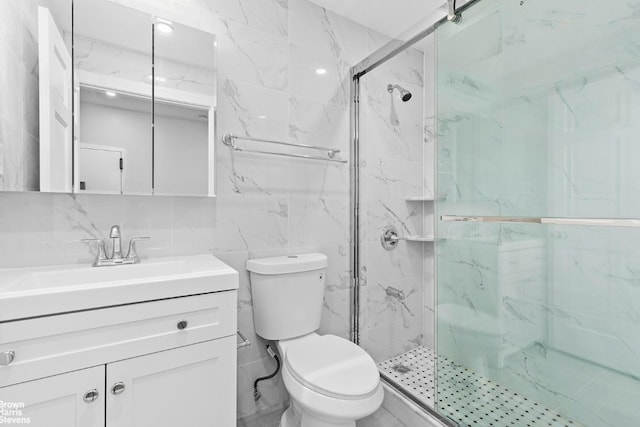 bathroom featuring tile walls, backsplash, vanity, toilet, and a shower with door