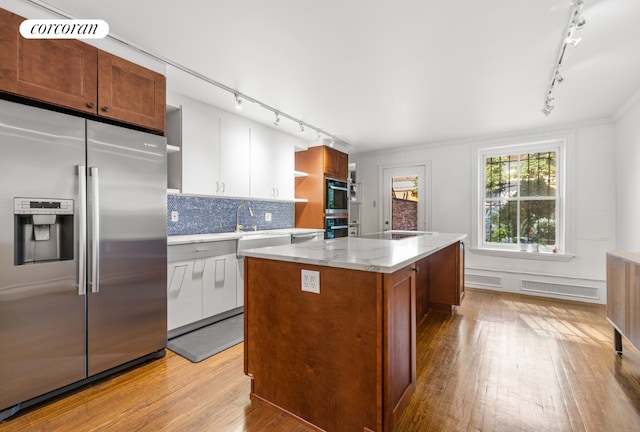 kitchen featuring stainless steel fridge, black electric stovetop, white cabinets, a kitchen island, and light hardwood / wood-style flooring