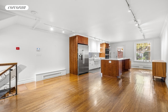 kitchen featuring high quality fridge, a center island, double oven, tasteful backsplash, and hardwood / wood-style flooring