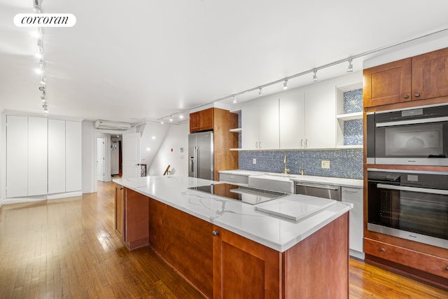 kitchen with white cabinets, a kitchen island, stainless steel appliances, tasteful backsplash, and sink