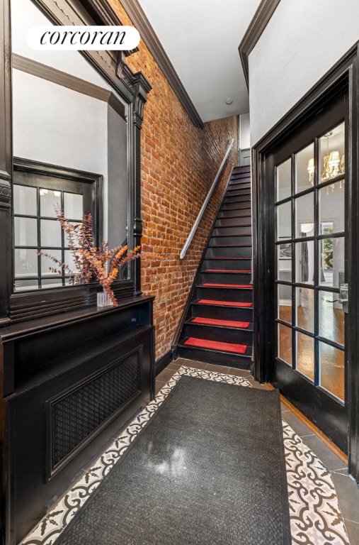 stairway featuring brick wall and crown molding