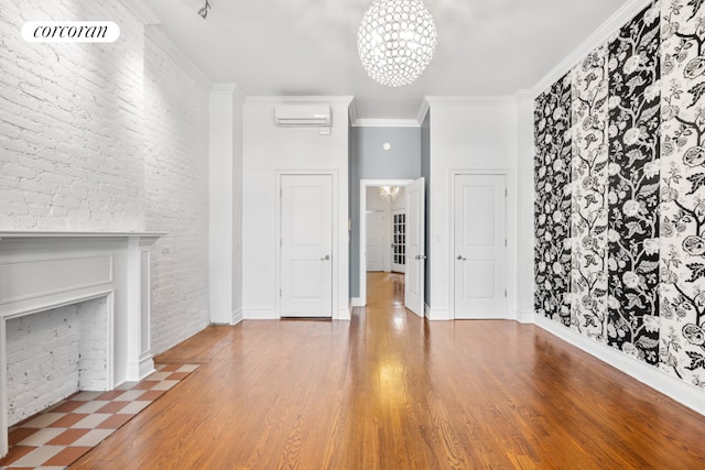 unfurnished living room with crown molding, a wall unit AC, hardwood / wood-style floors, and an inviting chandelier