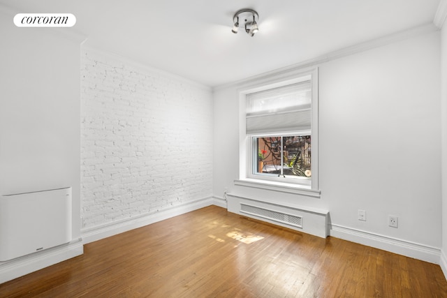 empty room with crown molding and wood-type flooring