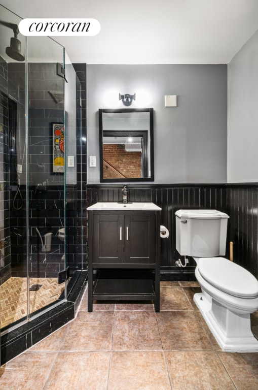 bathroom with toilet, vanity, tile patterned floors, and a shower with door