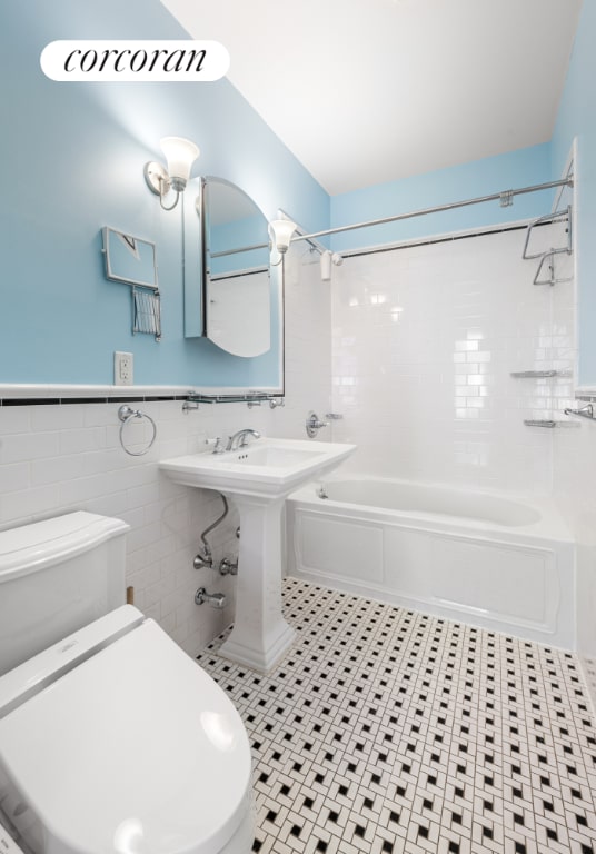 bathroom featuring toilet, tile patterned floors, tile walls, and tiled shower / bath