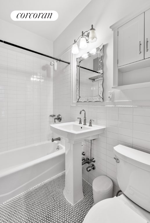 bathroom featuring toilet, tiled shower / bath, and tile walls