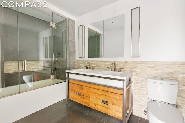 full bathroom with toilet, vanity, tile walls, tile patterned floors, and enclosed tub / shower combo