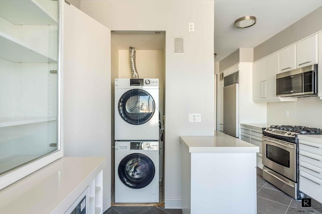 laundry room featuring stacked washer and clothes dryer and dark tile patterned flooring