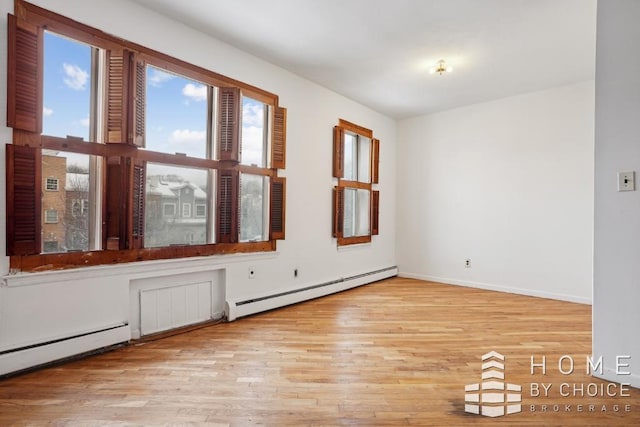 empty room featuring light wood-type flooring and a baseboard heating unit