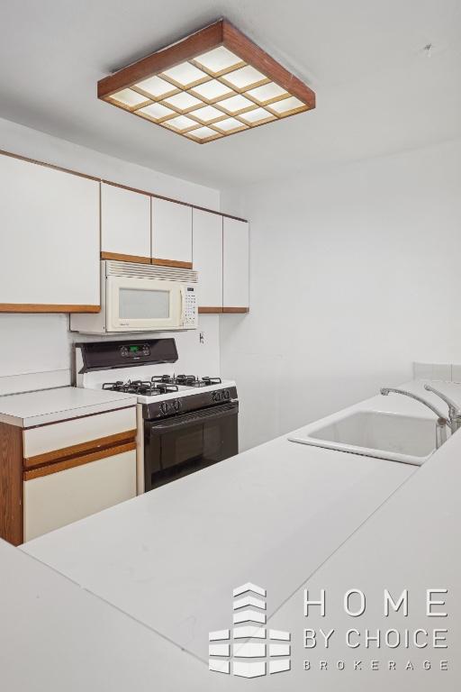 kitchen with sink, white appliances, and white cabinetry