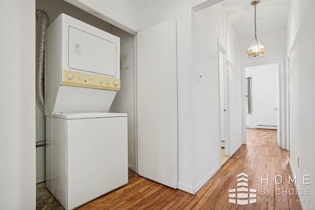 washroom with hardwood / wood-style flooring, a baseboard radiator, and stacked washer and clothes dryer