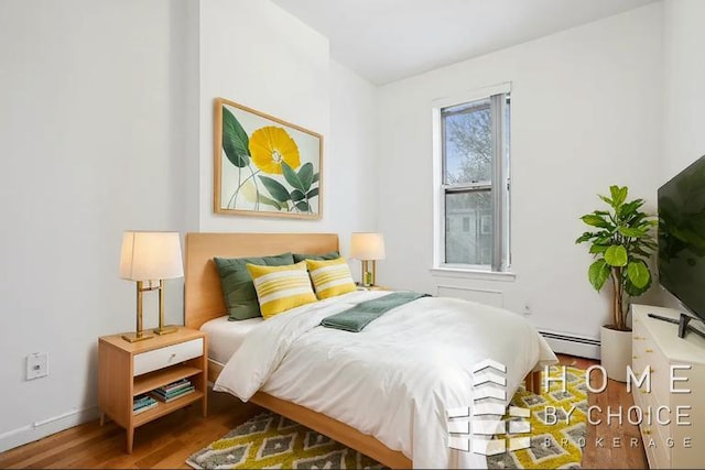 bedroom with a baseboard heating unit and wood-type flooring