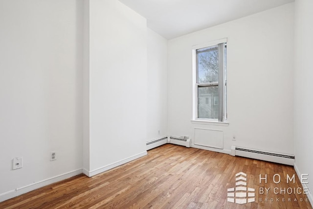 spare room with a baseboard heating unit and light hardwood / wood-style flooring