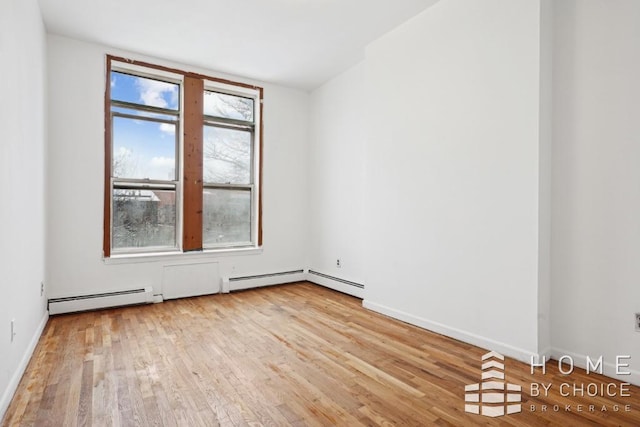 unfurnished room with a baseboard heating unit and light wood-type flooring