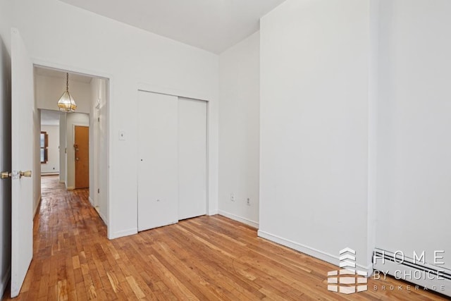 unfurnished bedroom featuring a closet, hardwood / wood-style floors, and a baseboard radiator